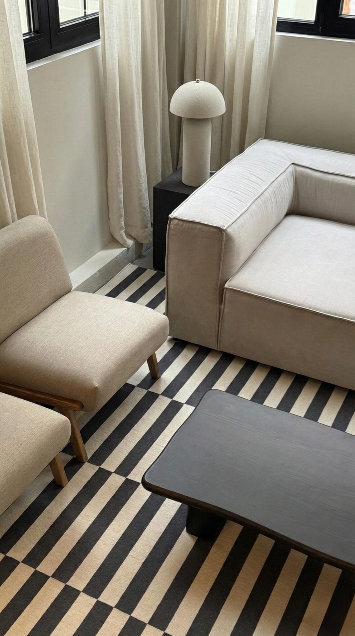 Interior diseñado por BPC Studio: sofá, butaca y lámpara sobre una alfombra a rayas
